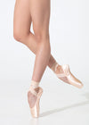 Dancer modeling satin pointe shoes en pointe against a light studio background.