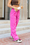 Adult dancer wearing bright pink cargo-style dance pants, standing outdoors.
