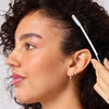 Model using a styling taming wand to smooth hair along the hairline