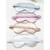 Love and Repeat satin sleeping masks arranged in assorted pink, white, champagne, and grey tones