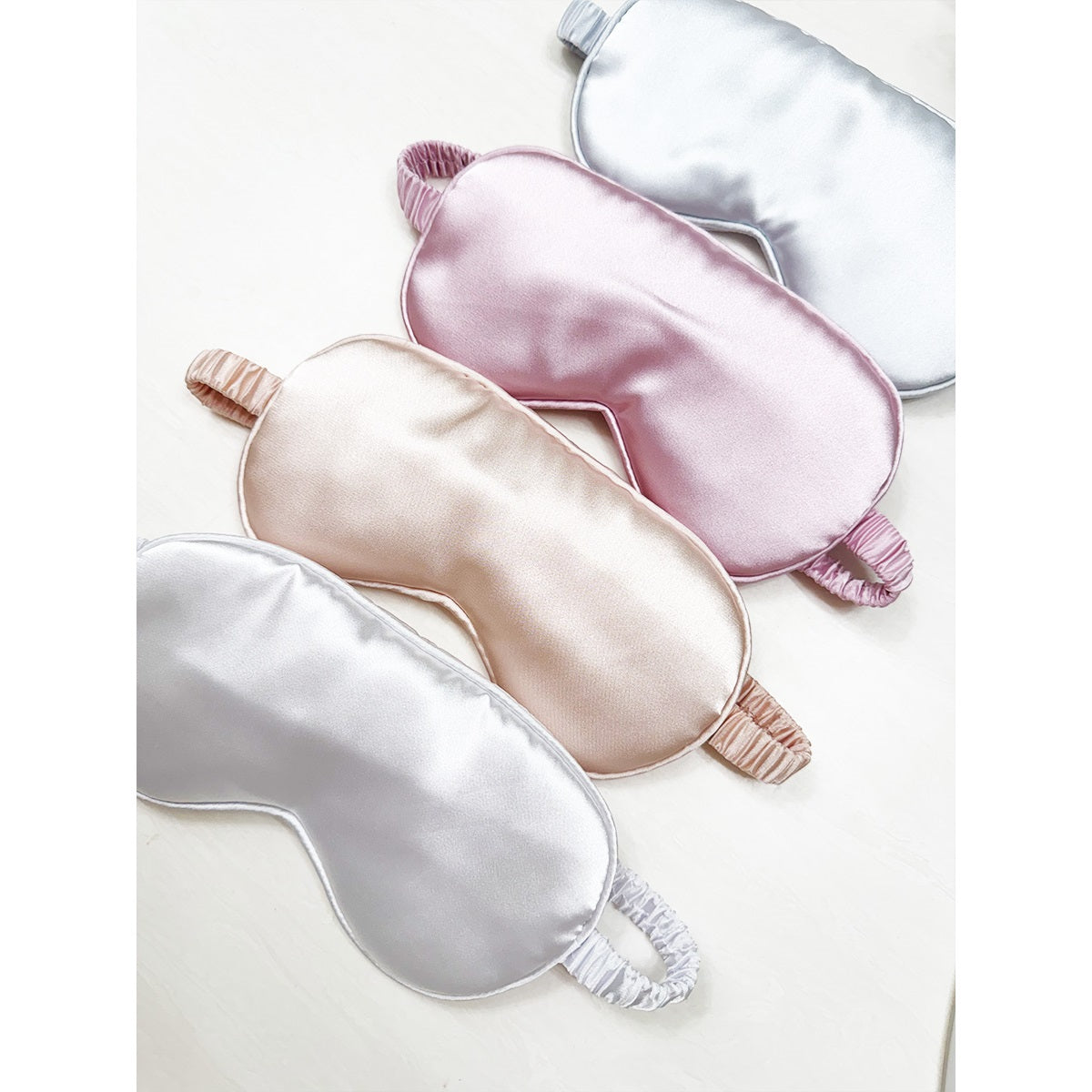 Love and Repeat satin sleeping eye masks in champagne, white, pink, and grey