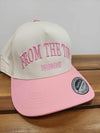 Cream and pink two-tone baseball cap with “FROM THE TOP” embroidered on the front, displayed on a wooden surface