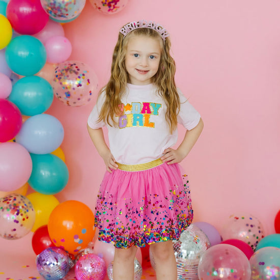 Young girl wearing raspberry confetti tutu at a colorful birthday celebration
