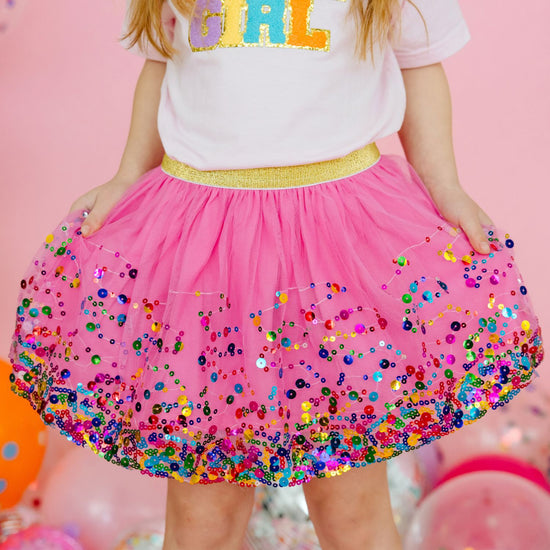 Close-up of raspberry pink tutu skirt showing colorful sequin embellishments and gold waistband