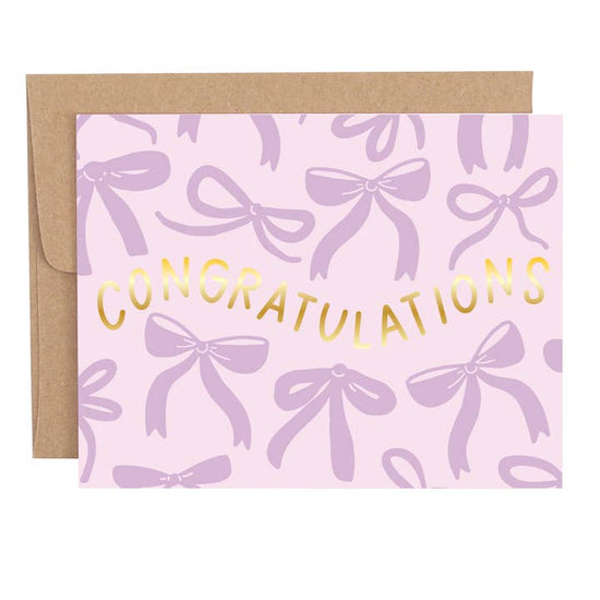 Congratulations greeting card with purple bow design and gold foil lettering displayed with envelope
