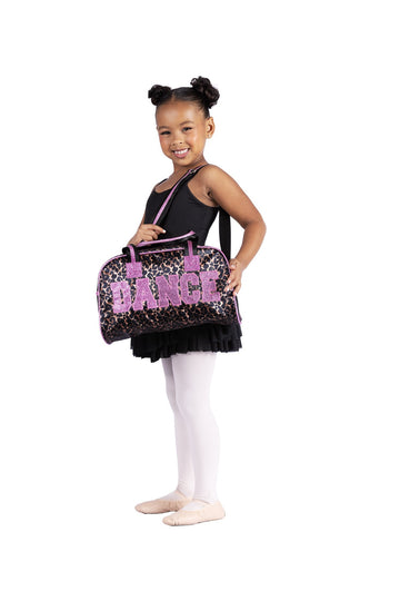 Young dancer holding black animal print dance duffle bag with pink “DANCE” lettering