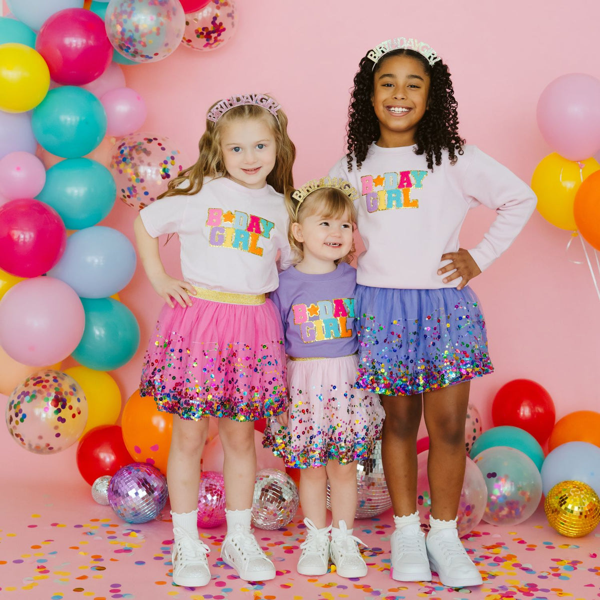 Three young girls modeling bright pink and pastel confetti tutu skirts