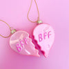 Close-up of two pink heart-shaped BFF ornaments with glitter lettering on a pink background.