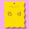 Gold huggie earrings displayed on a bright yellow scalloped backer card with Taylor Elliot Designs branding.