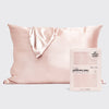 Blush satin pillowcase displayed on a bed with matching product packaging