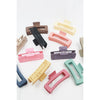 Love and Repeat matte hair claws displayed with assorted colorful hair accessories