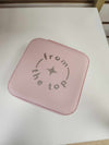 Closed pink jewelry box viewed from above with logo centered on the lid