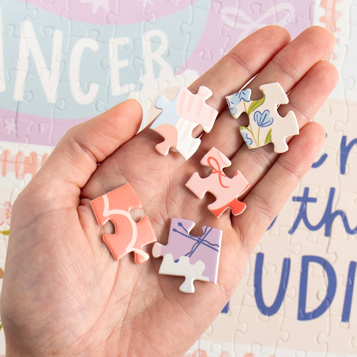 Hand holding pieces of the Dance It Out jigsaw puzzle during assembly