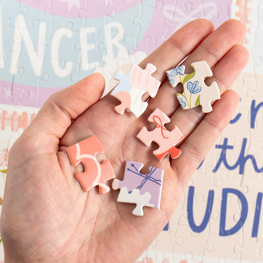 Hand holding pieces of the Dance It Out jigsaw puzzle during assembly