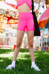 Adult dancer wearing bright pink dance shorts, standing outdoors on grass