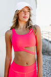 Adult dancer wearing a bright pink dance bra with matching bottoms, standing outdoors.