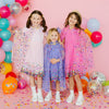 Two girls wearing pink and pastel dress-up capes with colorful confetti details
