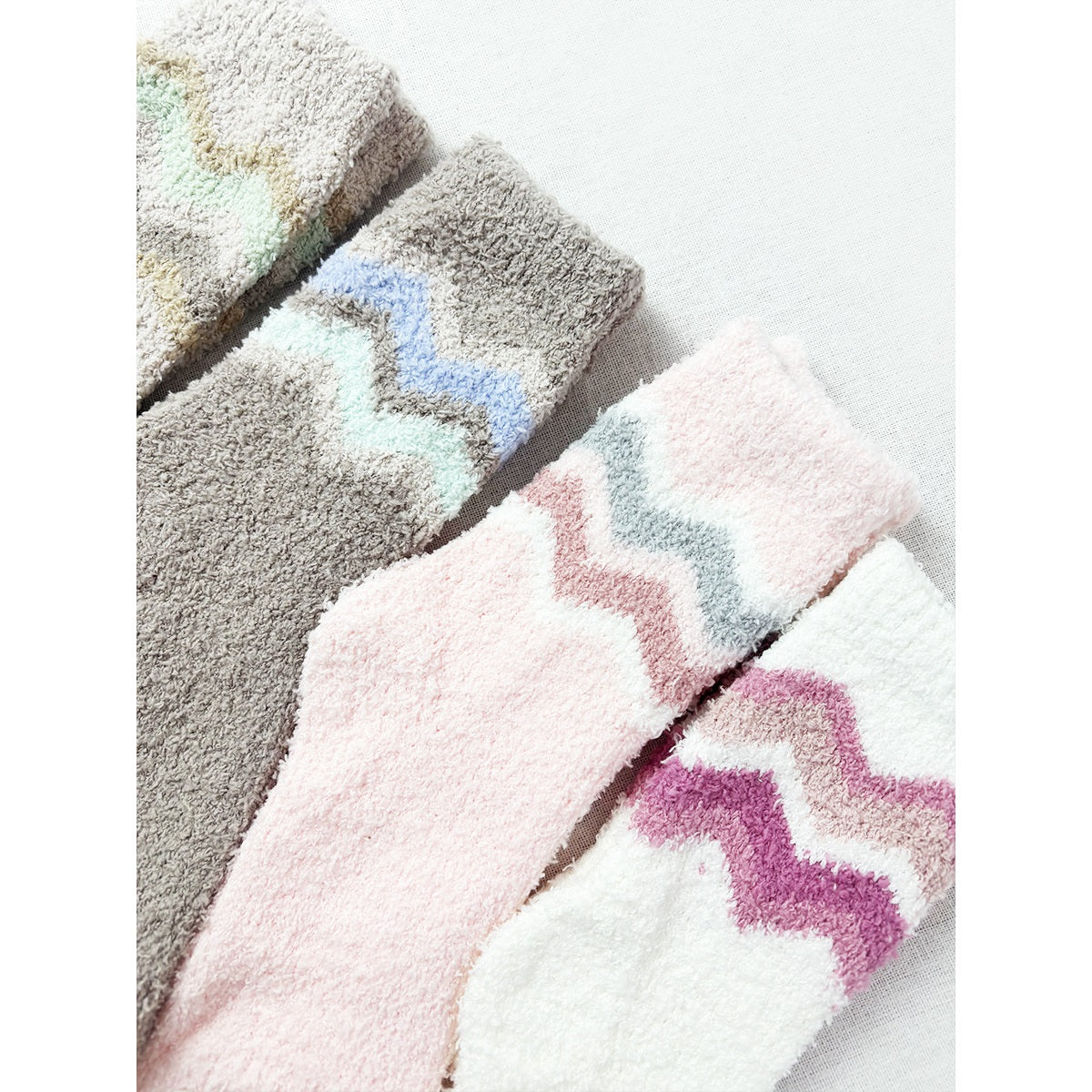 Close-up of assorted Love and Repeat plush socks in gray, pink, and white