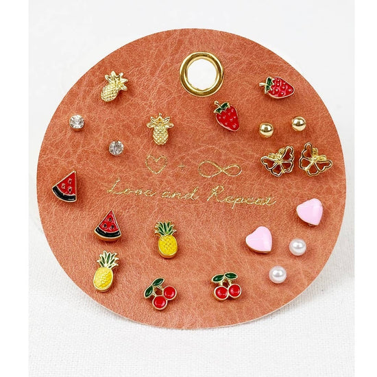 Love and Repeat Everyday Fruity Minimal Earrings featuring assorted gold-tone fruit studs with colorful strawberry, cherry, and miniature fruit designs displayed on a round jewelry card