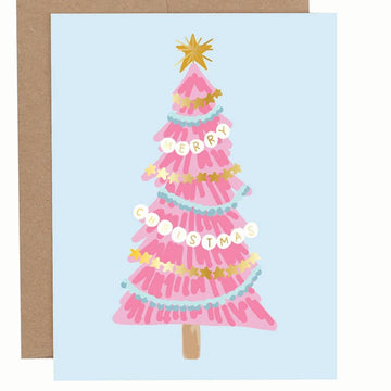 Greeting card with a pink Christmas tree illustrated with bracelet-style garlands and gold star topper on a light blue background, shown with a brown envelope.