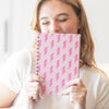 Person holding pink lightning bolt planner in front of their face