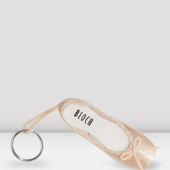 Bloch mini pointe shoe keychain in pink satin with fabric loop and metal key ring on a neutral background.