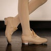 Child wearing tan tap shoes standing on studio floor