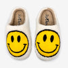 Pair of cream-colored fuzzy slippers with large yellow smiley faces on the top