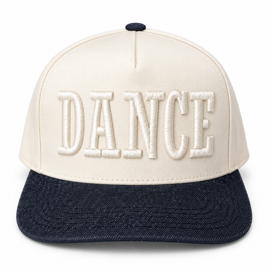 A structured baseball cap with an off-white crown featuring raised, embroidered block letters spelling 'DANCE' in white, and a dark navy blue denim-look flat brim.