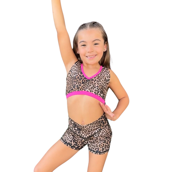 Young dancer wearing patterned V-waist dance shorts with coordinating top, posing in a dynamic stance.