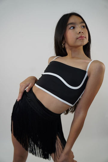 Model wearing a black wrap fringe skirt styled over dancewear, front view.
