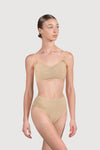 Dancer wearing a nude bandeau bra with matching briefs standing against a neutral background