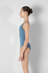 Child model wearing a light blue camisole leotard, shown from the side.