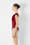 Side view of adult model wearing a red short sleeve leotard.