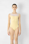 Adult model wearing a light neutral tank leotard with mesh back, shown from the front.