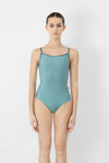 Child model wearing a teal camisole leotard, shown from the front.