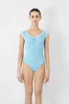 Adult model wearing a light blue cap sleeve leotard, shown from the front.