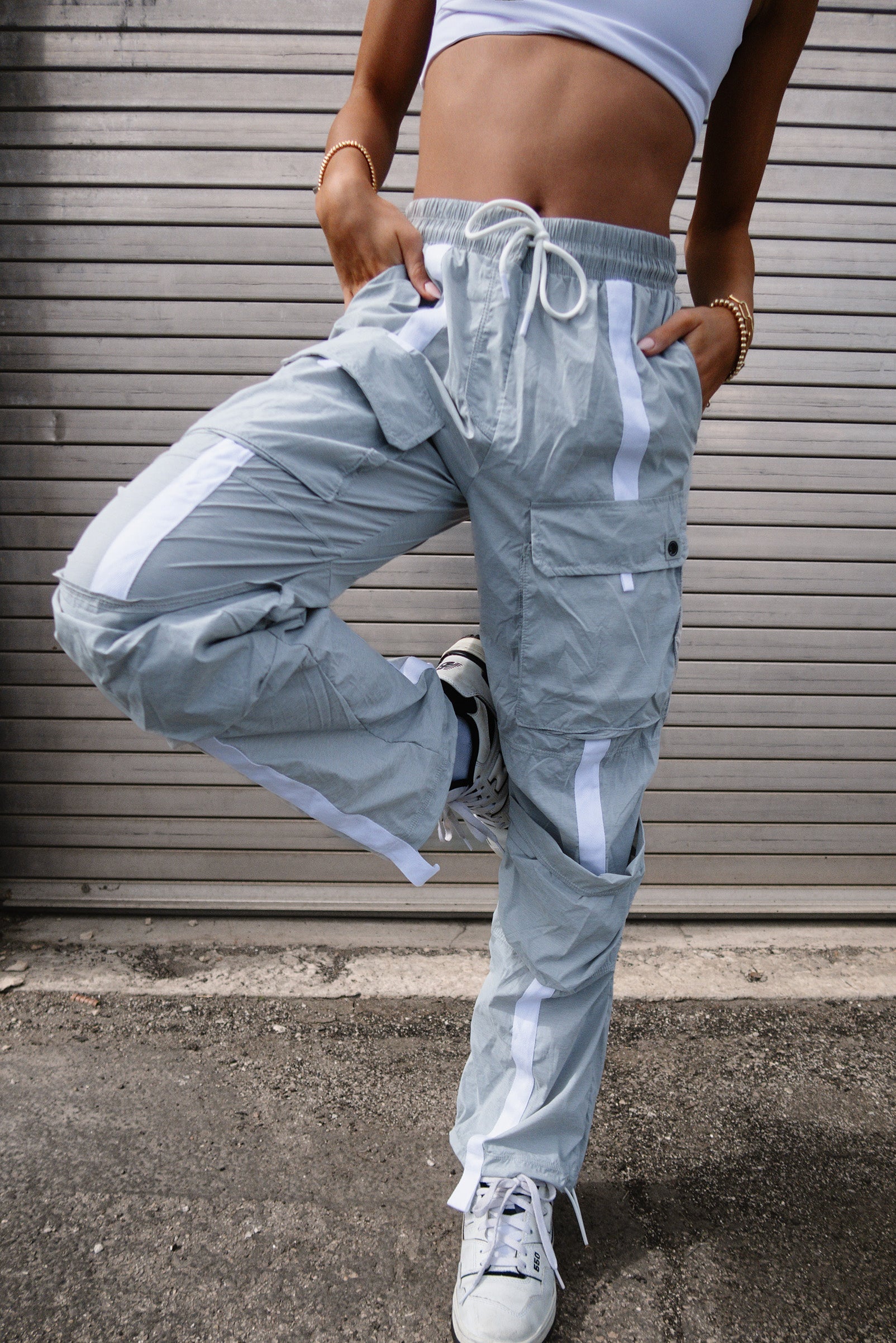Adult dancer wearing light gray cargo-style dance pants, standing outdoors near steps.