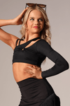 Adult dancer wearing a black asymmetrical one-shoulder crop top with a keyhole detail, posing with one arm raised.