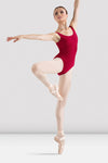 : Adult dancer wearing a red tank leotard with scoop neckline performing ballet pose