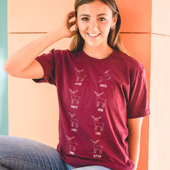Child wearing burgundy Covet Dance leaping reindeer holiday t-shirt