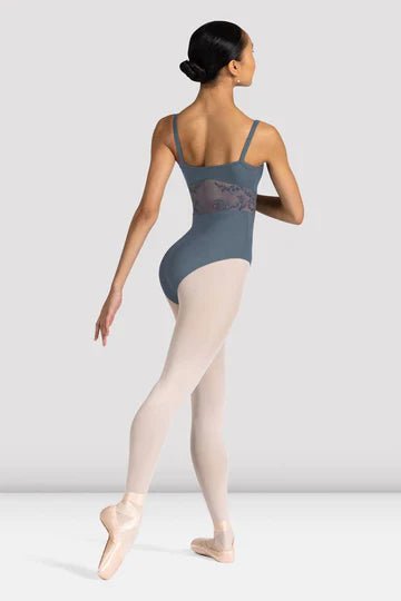Back view of young dancer wearing a black camisole leotard walking in ballet shoes and tights