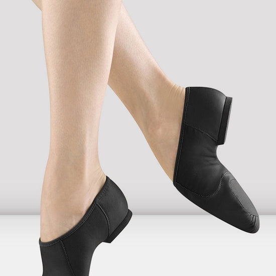 Black slip-on leather jazz shoes shown on a dancer’s feet.