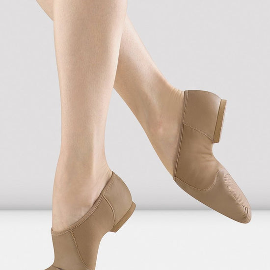 Tan slip-on leather jazz shoes shown on a dancer’s feet.
