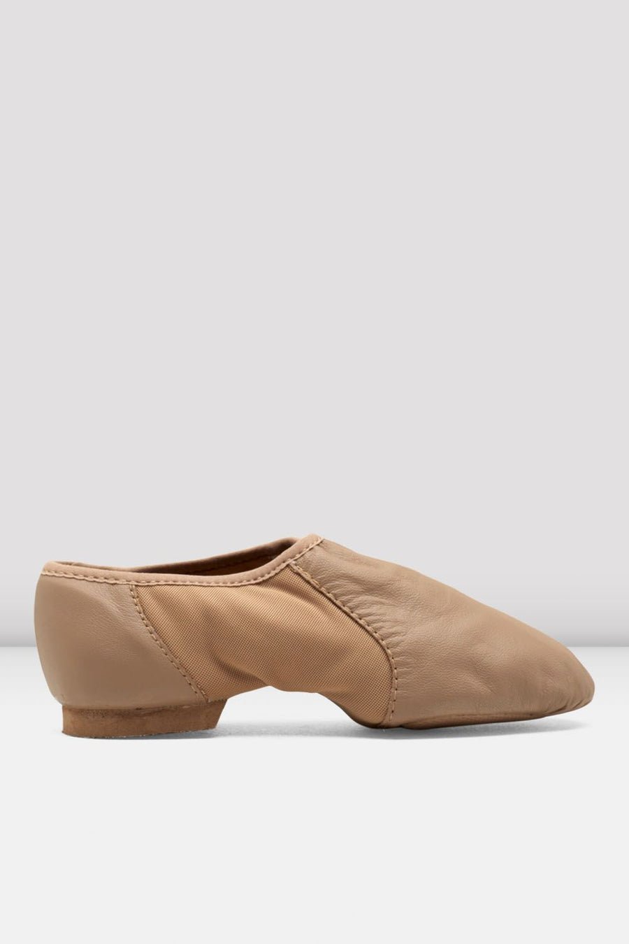 Side view of a tan slip-on leather jazz shoe on a white background.
