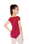 Child wearing red lace cap sleeve leotard in standing pose.