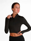 Side view of a dancer wearing a black zip crop jacket, highlighting fitted sleeves and cropped length.