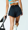 Black pleated dance shorts shown worn on a dancer walking