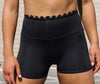 High-waisted black dance shorts with scalloped waistband detail shown from the front