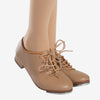 Caramel lace-up tap shoe worn on dancer’s foot